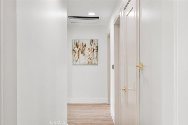 hallway featuring light wood-style floors, visible vents, and baseboards