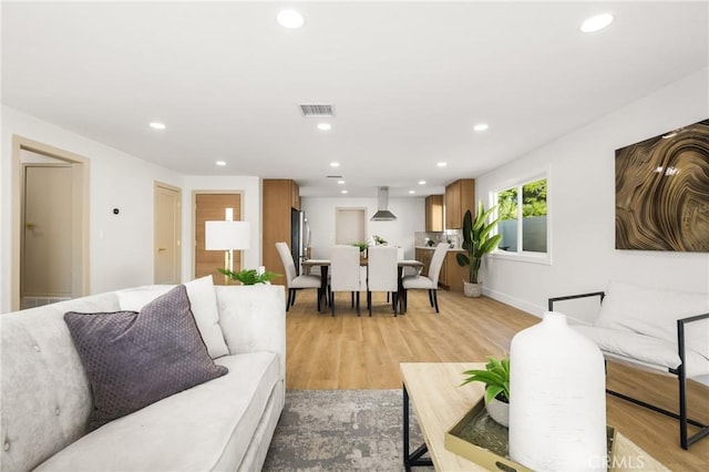 living room featuring light wood-style floors, recessed lighting, and visible vents