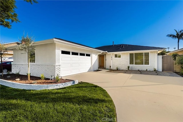 ranch-style house featuring brick siding, a gate, a garage, driveway, and a front lawn