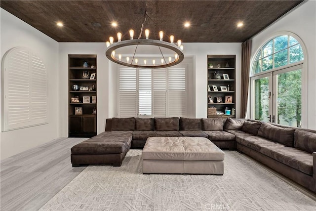 living room with built in shelves, a chandelier, french doors, and light hardwood / wood-style floors