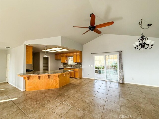 35777 Rd 606, Raymond, CA 93653 - kitchen featuring brown cabinets, a peninsula, tasteful backsplash, a kitchen breakfast bar, and light tile patterned floors