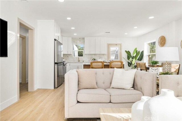 living room featuring a healthy amount of sunlight, sink, and light wood-type flooring