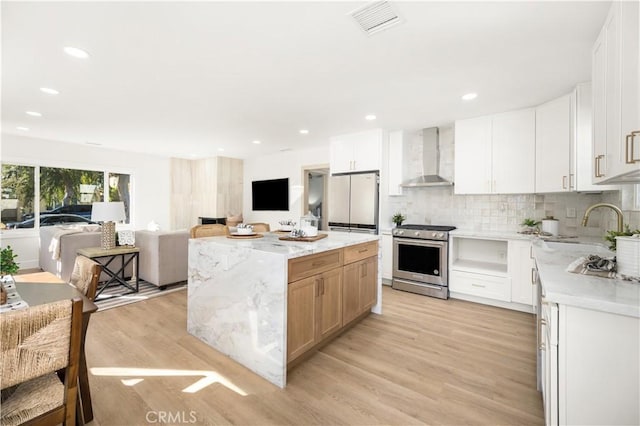 kitchen featuring white cabinets, sink, wall chimney exhaust hood, and high end stainless steel range oven