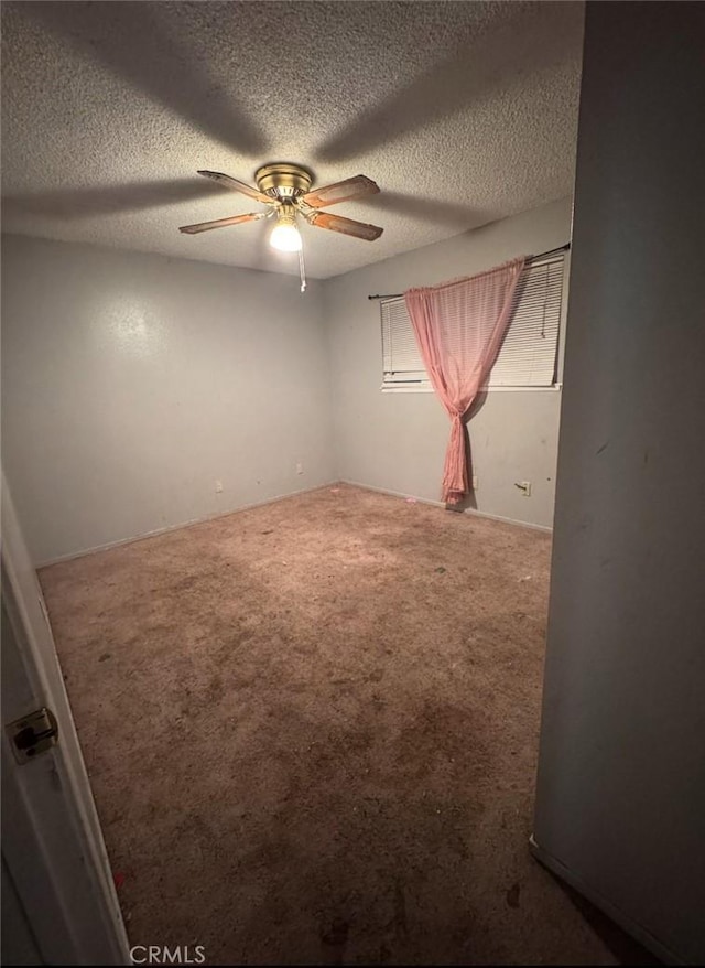 carpeted spare room featuring a textured ceiling and ceiling fan