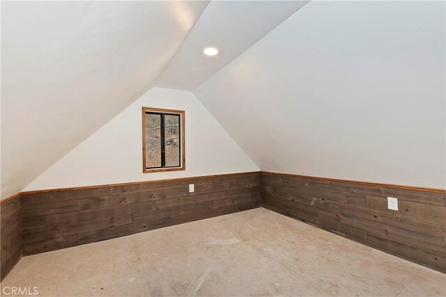 additional living space with wooden walls and vaulted ceiling