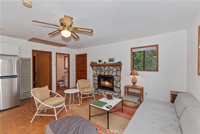 living room with ceiling fan, light wood-type flooring, and a fireplace