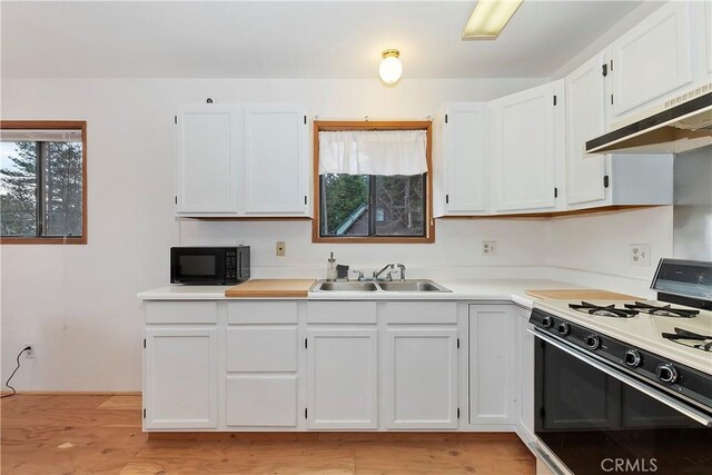 kitchen featuring white gas stove, white cabinetry, sink, and light hardwood / wood-style flooring