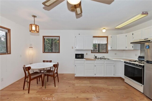 kitchen with gas range, white cabinetry, hanging light fixtures, and light hardwood / wood-style floors