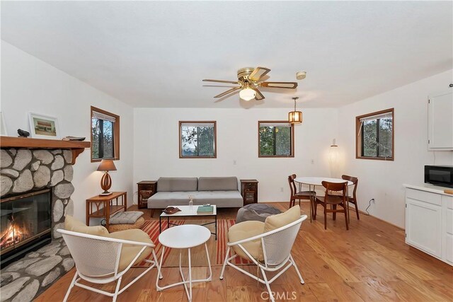 living room with ceiling fan, light wood-type flooring, and a fireplace