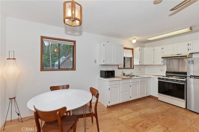 kitchen with stove, light wood-type flooring, sink, white cabinetry, and stainless steel refrigerator