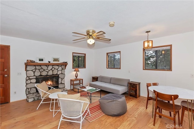 living room featuring a fireplace, light hardwood / wood-style floors, and ceiling fan