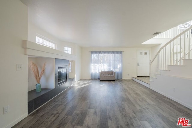 unfurnished living room featuring dark hardwood / wood-style flooring and a tiled fireplace