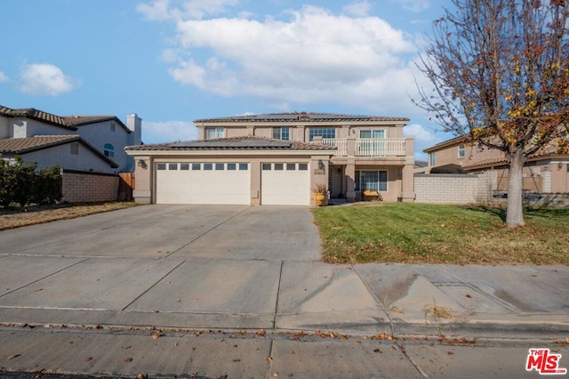 view of front of house featuring a garage, a balcony, and a front yard