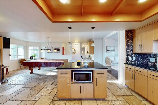 kitchen with pendant lighting, light brown cabinets, a tray ceiling, and stainless steel microwave