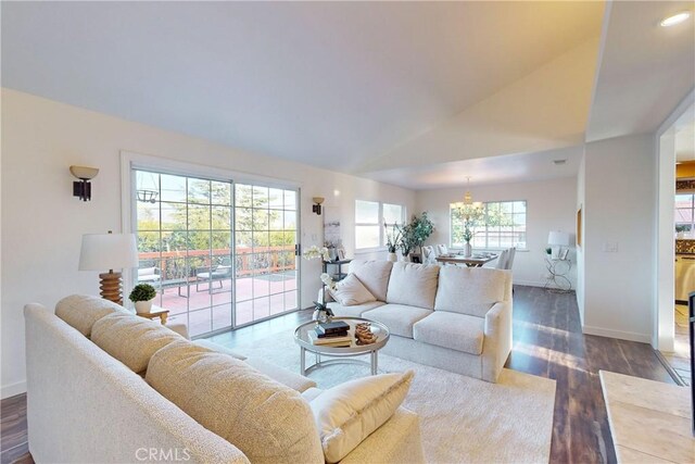 living room with an inviting chandelier, dark hardwood / wood-style flooring, and lofted ceiling