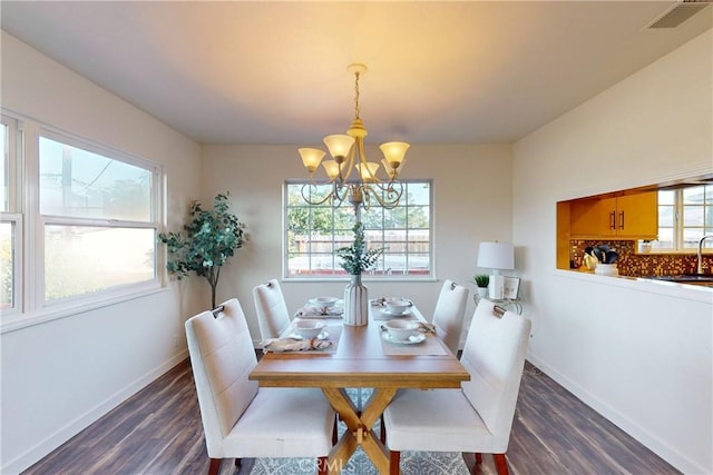 dining area with dark hardwood / wood-style floors and a notable chandelier