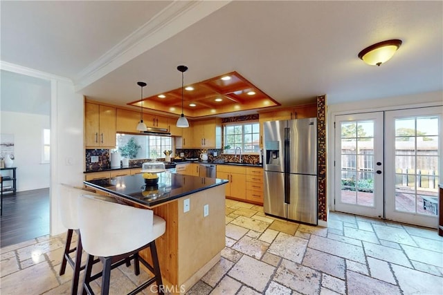 kitchen with appliances with stainless steel finishes, pendant lighting, tasteful backsplash, a kitchen bar, and a tray ceiling