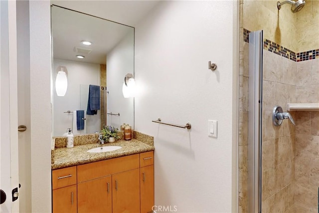 bathroom featuring a shower with door and vanity