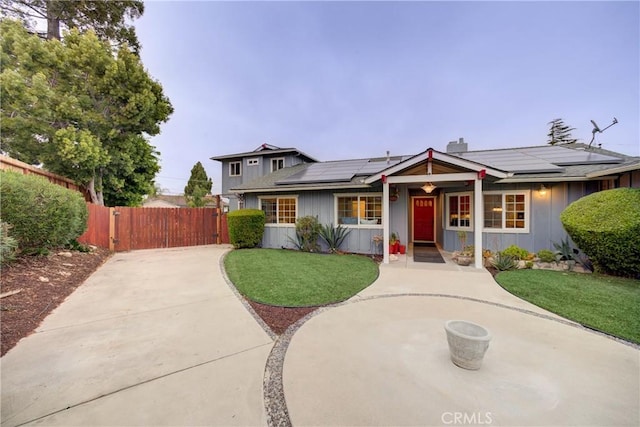 view of front of house with a front yard, solar panels, and covered porch