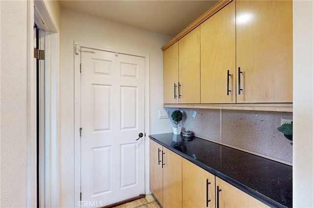 kitchen with decorative backsplash, light brown cabinetry, and dark stone counters