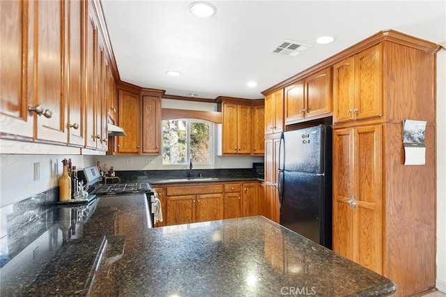 kitchen with black refrigerator, ornamental molding, sink, dark stone countertops, and stainless steel range with electric cooktop