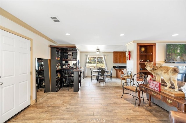 interior space with ceiling fan, light hardwood / wood-style flooring, and ornamental molding