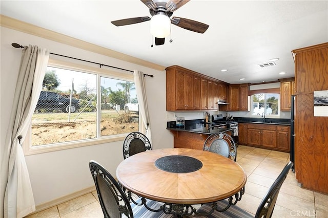 tiled dining area with plenty of natural light, ceiling fan, and sink