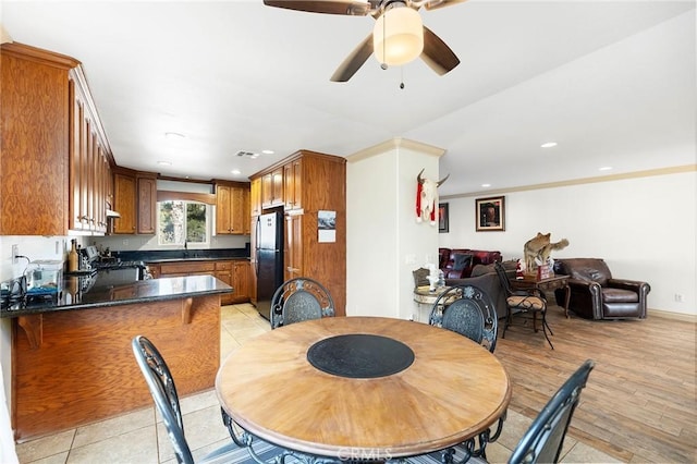 dining room featuring ceiling fan, light hardwood / wood-style floors, ornamental molding, and sink