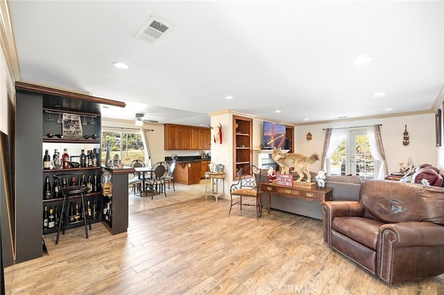 living room featuring light wood-type flooring, crown molding, ceiling fan, and a healthy amount of sunlight