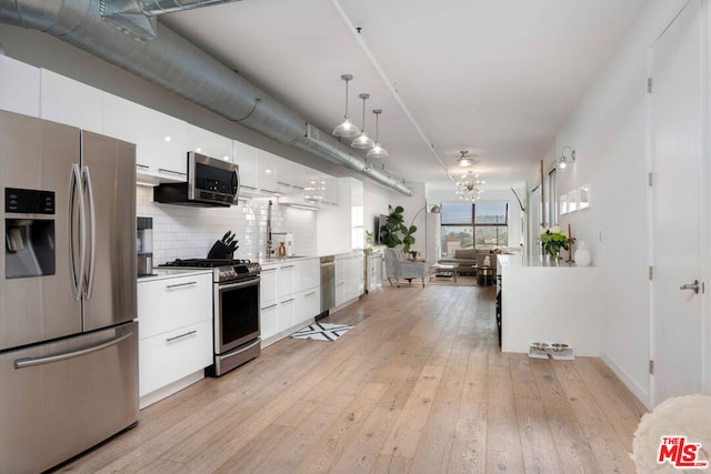 kitchen featuring pendant lighting, white cabinets, appliances with stainless steel finishes, tasteful backsplash, and light hardwood / wood-style floors