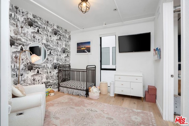 bedroom with a crib and light wood-type flooring