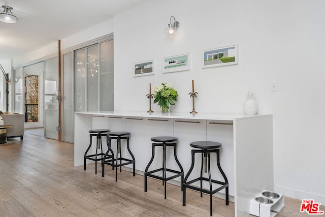 kitchen featuring a kitchen breakfast bar, kitchen peninsula, and light hardwood / wood-style flooring