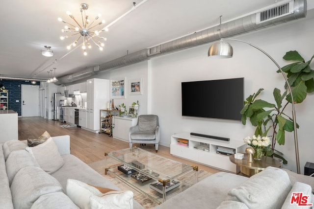 living room featuring an inviting chandelier and light hardwood / wood-style flooring