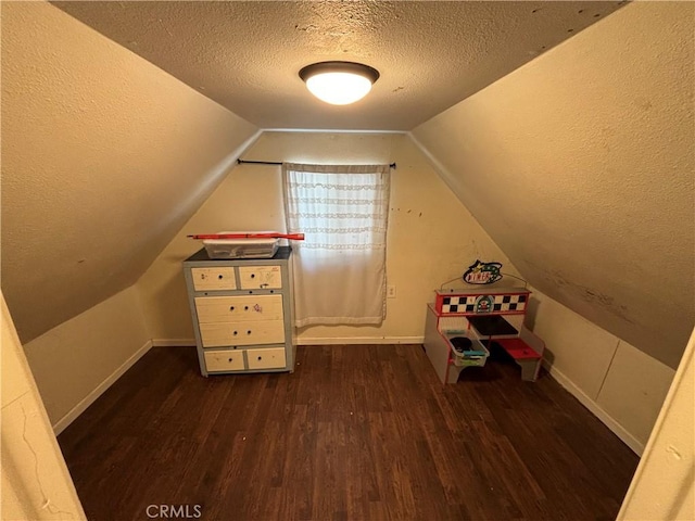 additional living space with a textured ceiling, dark wood-type flooring, and lofted ceiling