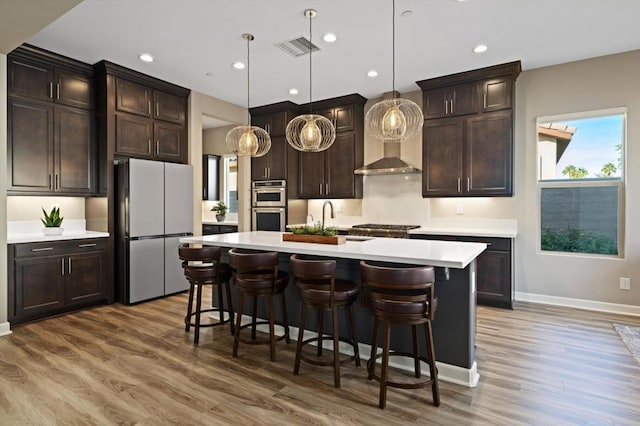 kitchen with hardwood / wood-style flooring, dark brown cabinets, an island with sink, decorative light fixtures, and white fridge