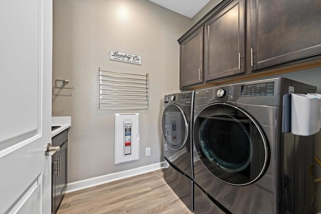 laundry area with cabinets, washer and clothes dryer, and light wood-type flooring