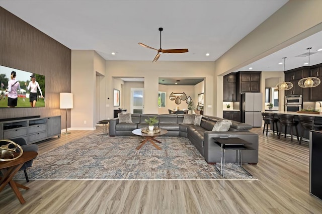 living room with light wood-type flooring, wooden walls, and ceiling fan