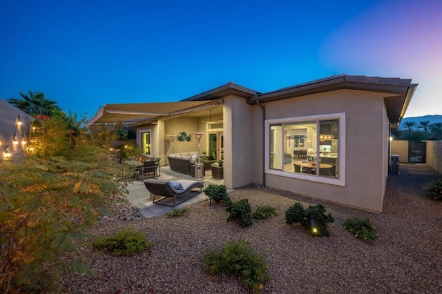 back house at dusk with a patio area