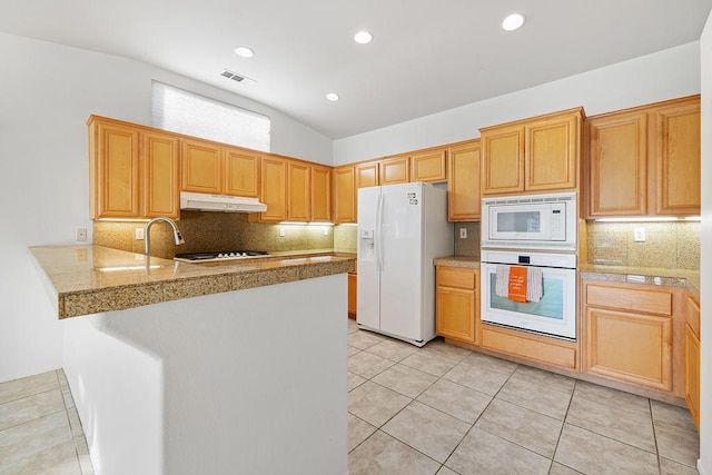 kitchen with kitchen peninsula, lofted ceiling, white appliances, decorative backsplash, and light tile patterned flooring