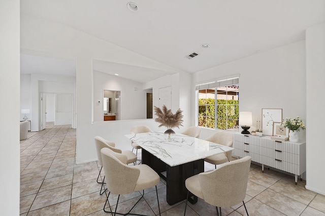 tiled dining area featuring vaulted ceiling