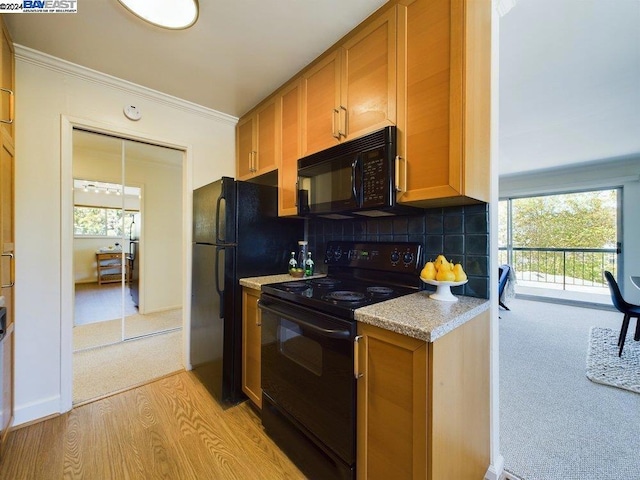 kitchen featuring light colored carpet, black appliances, crown molding, and tasteful backsplash