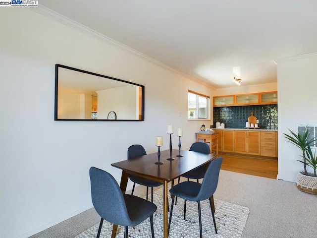 carpeted dining room with ornamental molding