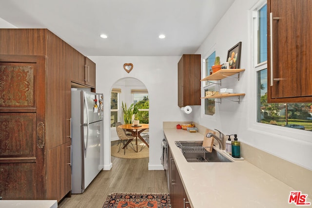 kitchen with stainless steel fridge, sink, and light wood-type flooring