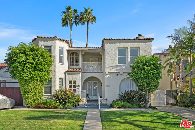 mediterranean / spanish-style home with a balcony, french doors, and a front yard