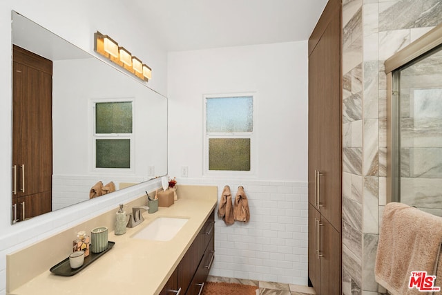 bathroom with tile patterned floors, vanity, tile walls, and walk in shower