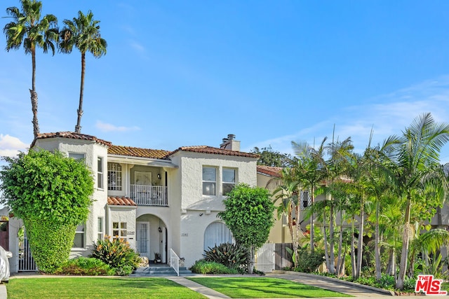 mediterranean / spanish house with a balcony and a front lawn