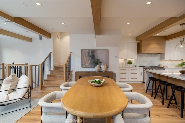 dining area featuring beamed ceiling and light hardwood / wood-style flooring