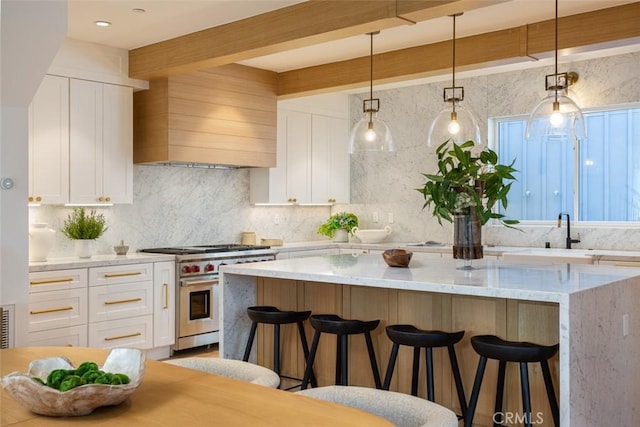 kitchen with custom range hood, high end stove, beam ceiling, decorative light fixtures, and white cabinets