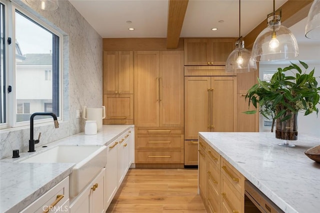 kitchen featuring light stone countertops, beamed ceiling, pendant lighting, paneled built in fridge, and light wood-type flooring