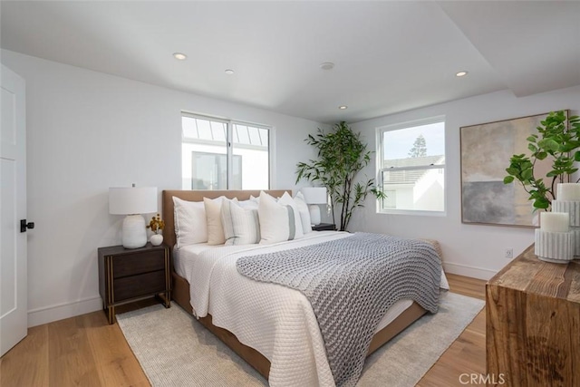 bedroom with light hardwood / wood-style floors and multiple windows